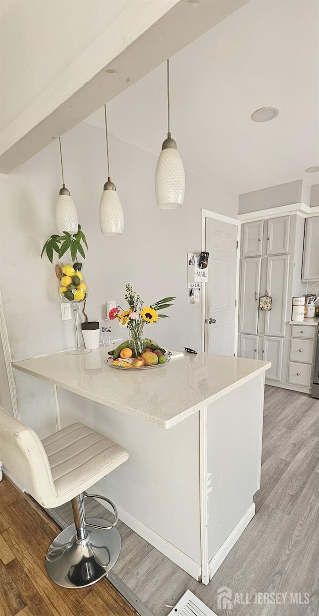 789 Barry Ave, Perth Amboy, NJ 08861 - kitchen with light wood finished floors, a breakfast bar area, decorative light fixtures, and light stone countertops
