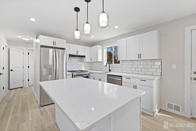 kitchen with sink, white cabinetry, stainless steel appliances, and a kitchen island