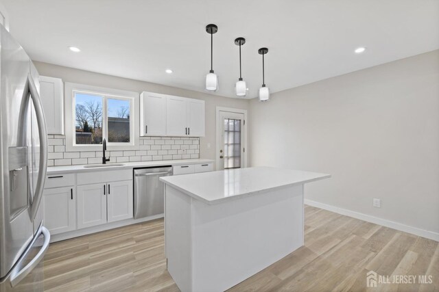 kitchen featuring white cabinets, backsplash, stainless steel appliances, and a center island