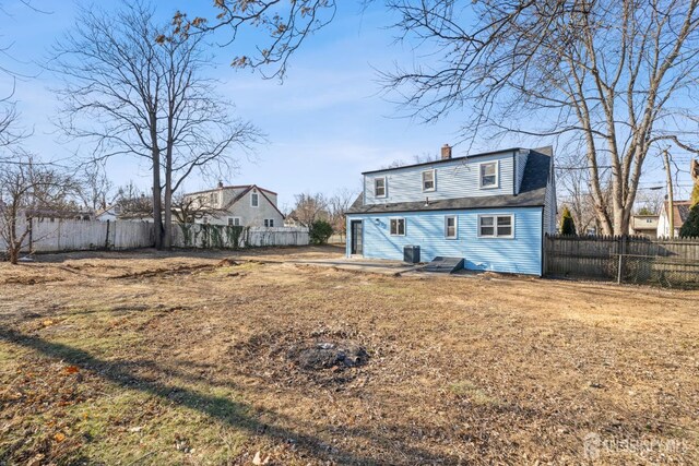 rear view of property with central AC and a lawn