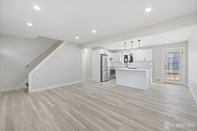 kitchen featuring appliances with stainless steel finishes, a kitchen island, decorative light fixtures, white cabinetry, and decorative backsplash