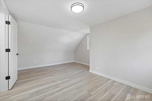 additional living space with vaulted ceiling and light hardwood / wood-style flooring