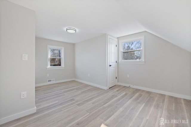 additional living space with vaulted ceiling and light wood-type flooring