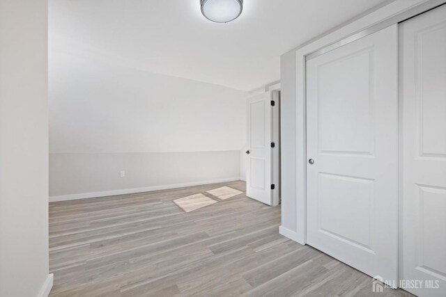 unfurnished bedroom with light wood-type flooring, a closet, and vaulted ceiling