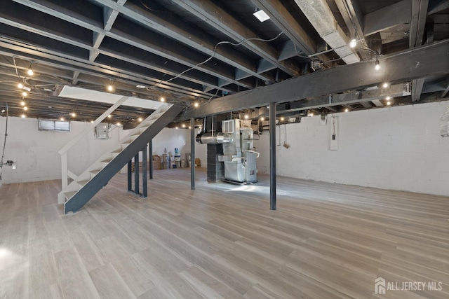 basement with electric panel, heating unit, and hardwood / wood-style flooring