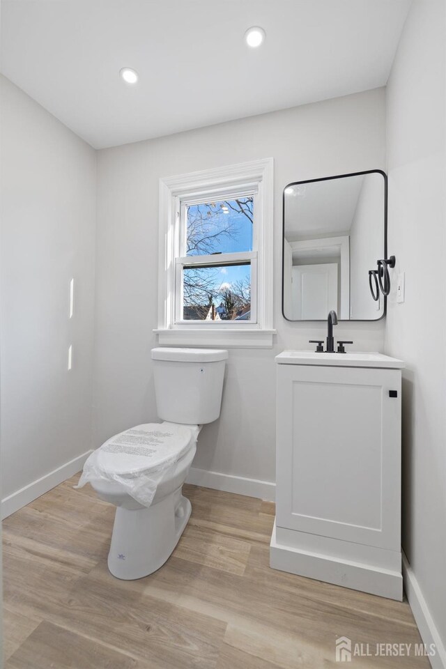 bathroom with hardwood / wood-style floors, toilet, and vanity