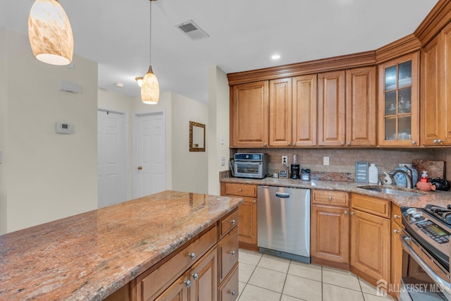 kitchen with light stone countertops, visible vents, a sink, stainless steel appliances, and backsplash