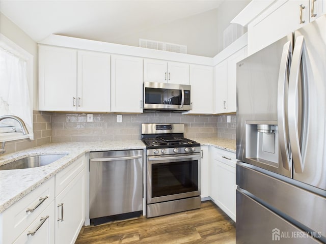 kitchen with visible vents, white cabinetry, a sink, appliances with stainless steel finishes, and backsplash