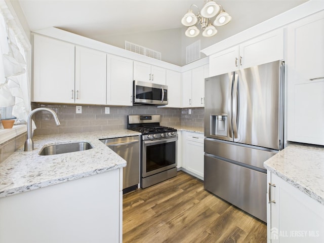kitchen featuring white cabinets, appliances with stainless steel finishes, a sink, decorative backsplash, and visible vents