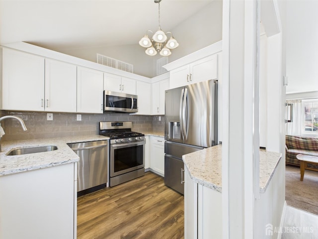 kitchen featuring decorative backsplash, wood finished floors, white cabinets, a sink, and stainless steel appliances