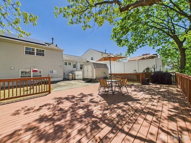 wooden deck featuring a storage shed, an outbuilding, and outdoor dining space