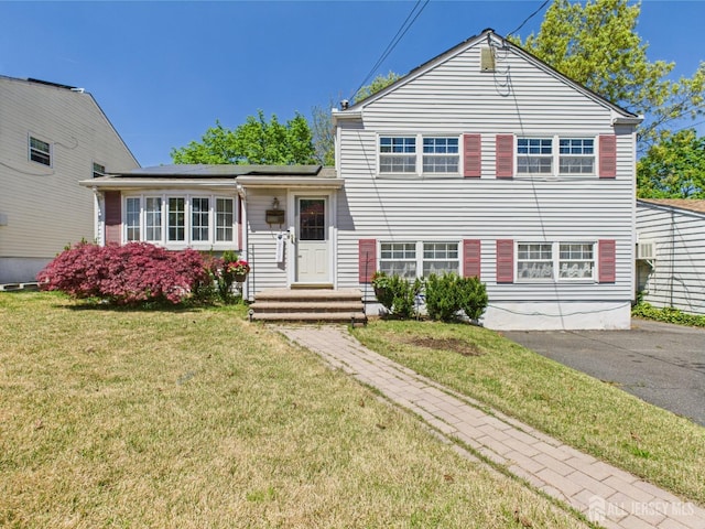 split level home featuring solar panels and a front yard