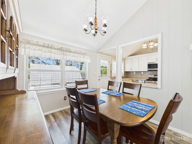 dining space with baseboards, a chandelier, light wood finished floors, and high vaulted ceiling