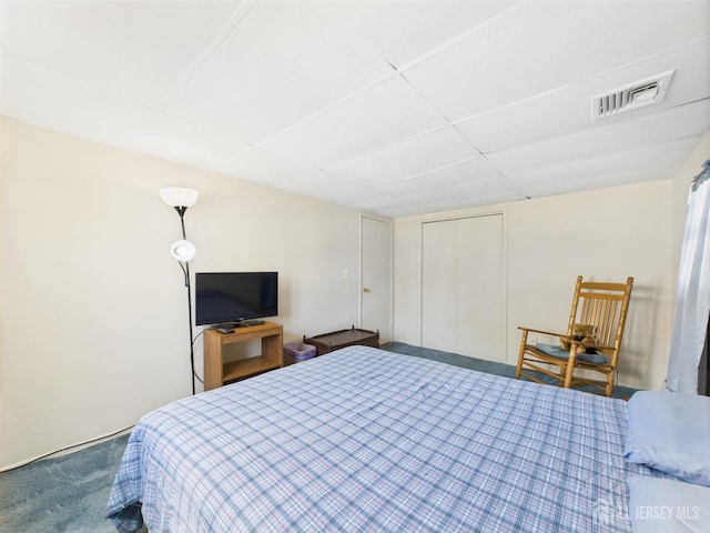 bedroom featuring visible vents, carpet flooring, a paneled ceiling, and a closet