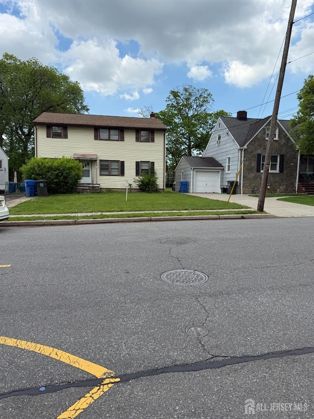 view of front of house with an outbuilding, a front lawn, concrete driveway, a chimney, and a garage