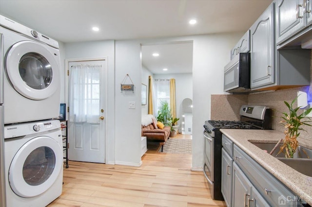 washroom with light wood-type flooring and stacked washer and clothes dryer