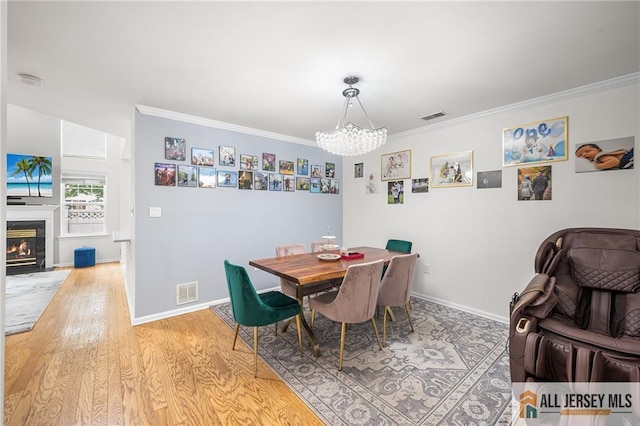 202 Canterbury Way S, Brunswick, NJ 08540 - dining space with a chandelier, light wood finished floors, crown molding, baseboards, and a fireplace with flush hearth
