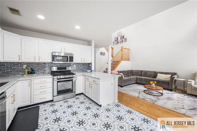 202 Canterbury Way S, Brunswick, NJ 08540 - kitchen featuring appliances with stainless steel finishes, open floor plan, white cabinetry, a peninsula, and backsplash