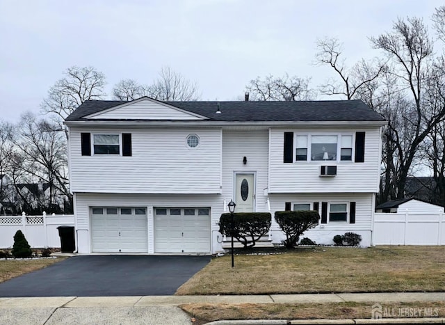 split foyer home with driveway, an attached garage, a front lawn, and fence