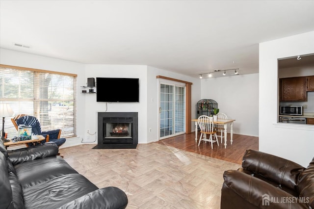 living area featuring a fireplace with flush hearth, visible vents, and track lighting