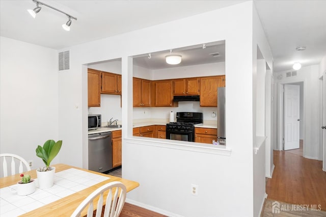 kitchen with appliances with stainless steel finishes, brown cabinetry, visible vents, and under cabinet range hood