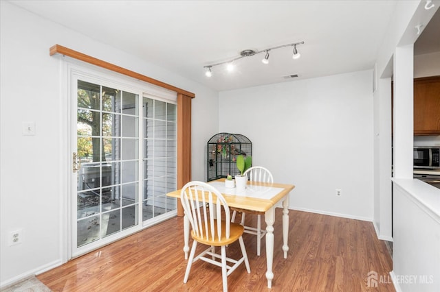 dining area featuring light wood-style flooring, visible vents, baseboards, and track lighting