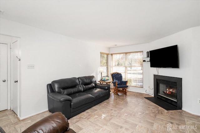 living area featuring a fireplace with flush hearth and baseboards