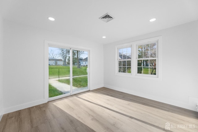 unfurnished room with healthy amount of natural light, wood finished floors, baseboards, and recessed lighting