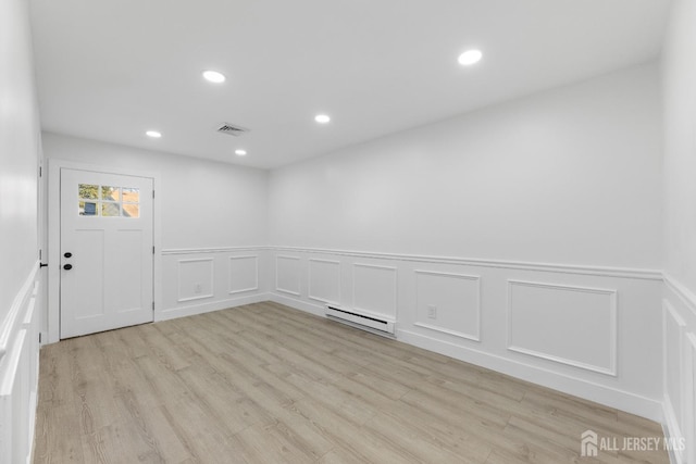 unfurnished room with a baseboard radiator, light wood-style flooring, wainscoting, recessed lighting, and a decorative wall