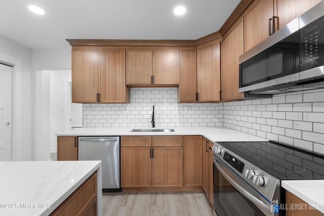 kitchen with appliances with stainless steel finishes, a sink, light wood-type flooring, light countertops, and recessed lighting