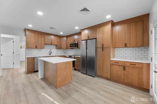 kitchen featuring appliances with stainless steel finishes, a center island, decorative backsplash, brown cabinetry, and recessed lighting
