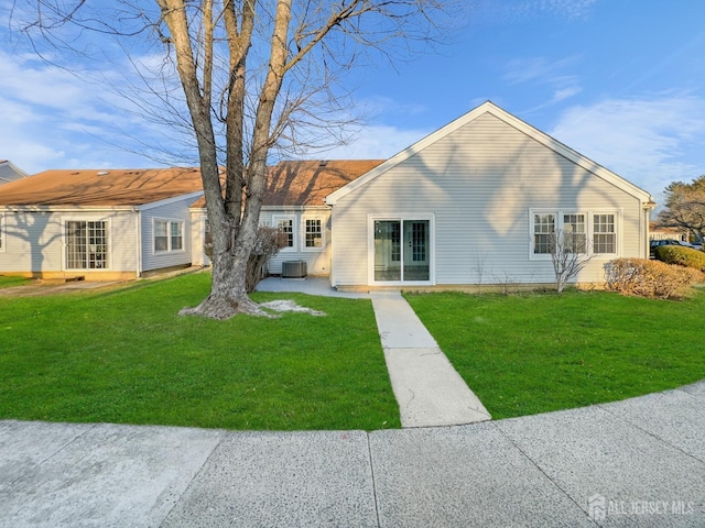 rear view of property with a lawn and central air condition unit