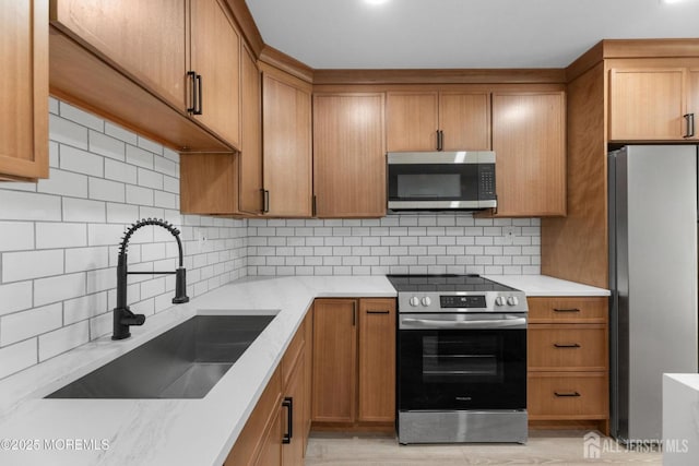kitchen featuring stainless steel appliances, a sink, brown cabinets, and backsplash
