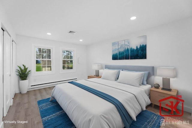 bedroom with a baseboard heating unit, light wood-style floors, and recessed lighting