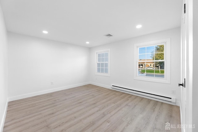 empty room featuring baseboard heating, light wood-style floors, recessed lighting, and baseboards