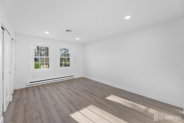 unfurnished bedroom with a baseboard heating unit, light wood-type flooring, recessed lighting, and baseboards
