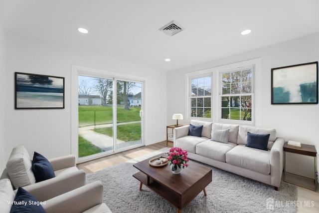 living area featuring recessed lighting, plenty of natural light, light wood-style flooring, and baseboards