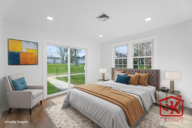 bedroom with access to outside, multiple windows, wood finished floors, and recessed lighting