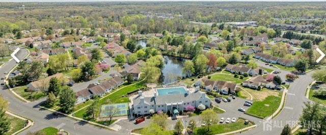 aerial view of property's location with a heavily wooded area, nearby suburban area, a pool area, and a nearby body of water