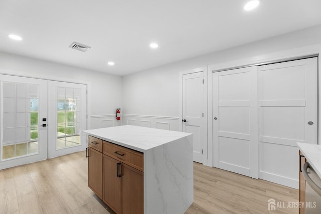 kitchen with french doors, light wood-style flooring, wainscoting, recessed lighting, and a kitchen island
