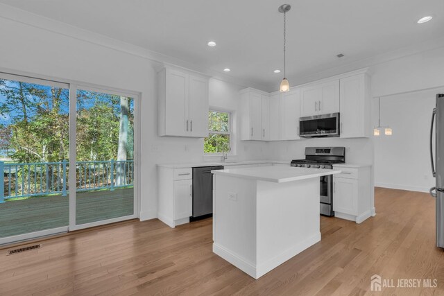 kitchen featuring a center island, white cabinets, stainless steel appliances, and light hardwood / wood-style floors