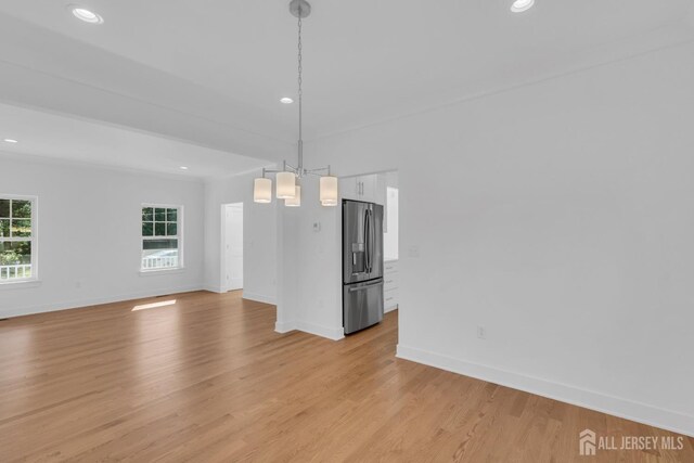 unfurnished dining area featuring a notable chandelier and light hardwood / wood-style flooring