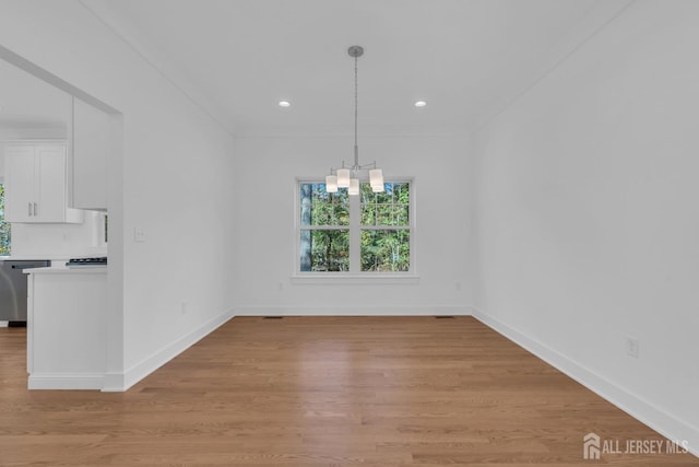 unfurnished dining area featuring light hardwood / wood-style flooring, a notable chandelier, and crown molding