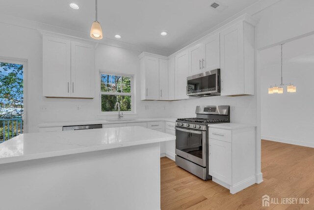 kitchen featuring white cabinetry, appliances with stainless steel finishes, and hanging light fixtures