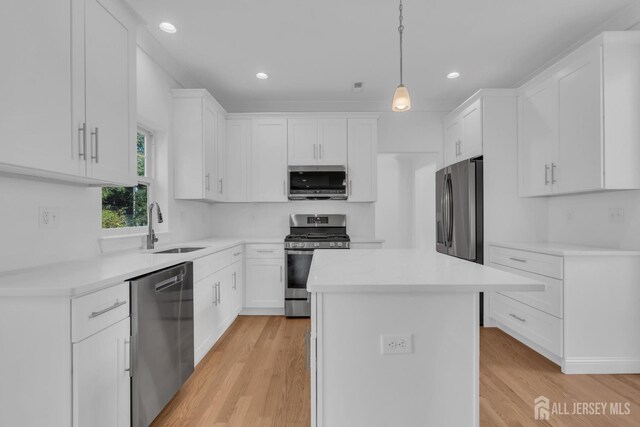 kitchen featuring light hardwood / wood-style floors, appliances with stainless steel finishes, a center island, and white cabinets