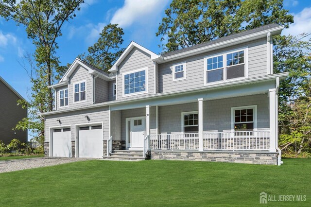 view of front of property featuring a garage, a front lawn, and a porch