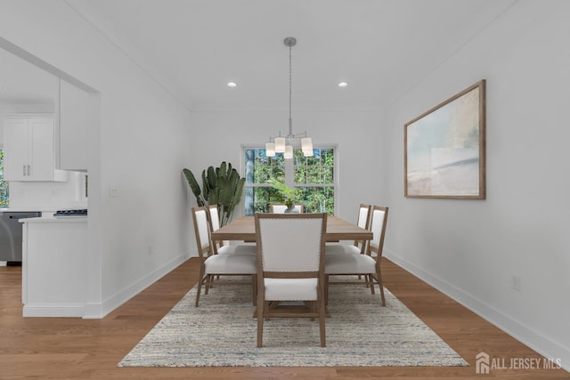 dining room with a notable chandelier, ornamental molding, and light wood-type flooring