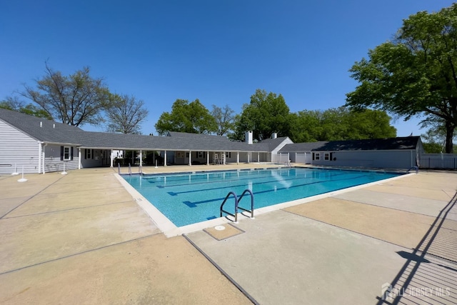 pool with a patio area and fence