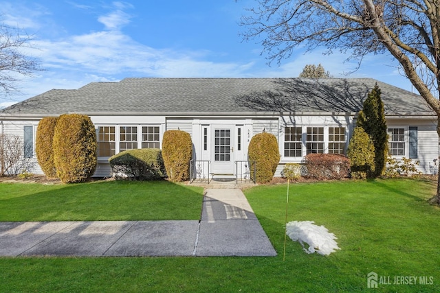 view of front of property with a shingled roof and a front yard