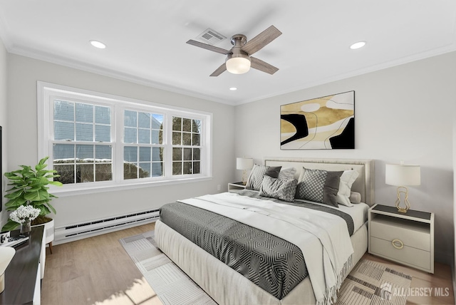 bedroom with a baseboard heating unit, wood finished floors, visible vents, and crown molding